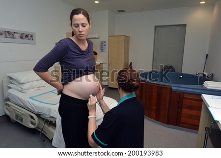 AUCKLAND - JUNE 07 2014:Midwife checks newborn heart beat in birthing suite of Maternity Hospital.In the 1960s, Igor Tjarkovsky,swimming instructor and midwife, popularized water birth in Russia.