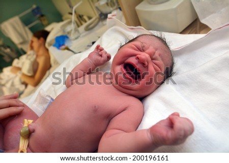 AUCKLAND - JUNE 07 2014:Newborn (Naomi Ben Ari age 0) screams during childbirth examination.About 370,000 babies born every day worldwide.The current births worldwide is estimated 134 million per year.