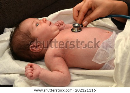 Midwife checks newborn baby heart beat.