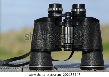 Binoculars field glasses against blue sky. Concept photo of adventure, search and exploring outdoor.