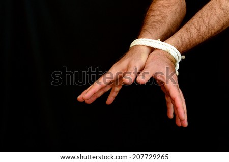 Hands of a missing kidnapped, abused, hostage, victim man  tied up with rope in emotional stress and pain, afraid, restricted, trapped, call for help, struggle, terrified, locked in a cage cell.