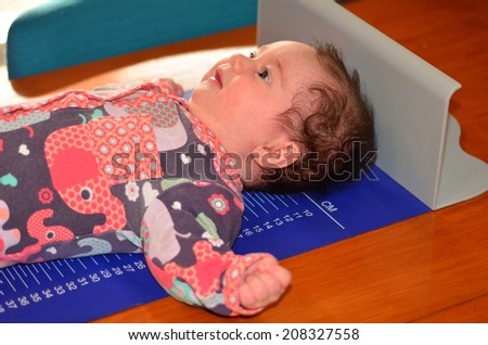 Infant baby on ruler measure during body development and body height examination.