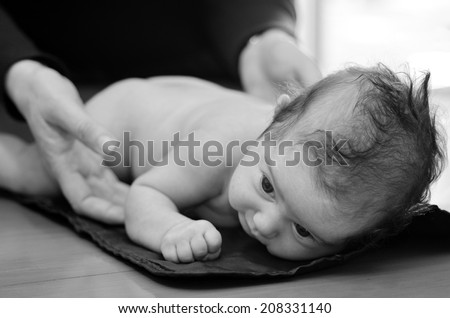 Hands of pediatrician nurse checks infant baby body development examination. (BW)