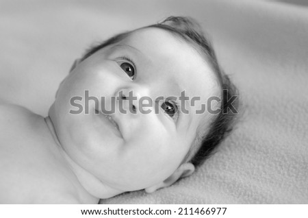 Infant baby face looks away. Concept photo of infant baby childhood healthcare development. Copy space. (BW)