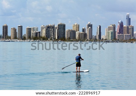 GOLD COAST - SEP 27 2014:Man on stand up paddling in Surfers Paradise. It\'s one of Australia\'s iconic coastal tourist destinations, drawing 10 million tourists every year from all over the world.