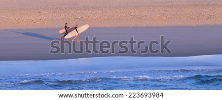 GOLD COAST - OCT 13 2014: Man and woman surfers with surfing boards  walks along the Spit beach.It is a very popular surfing beach in Surfers Paradise Gold Coast Queensland, Australia.