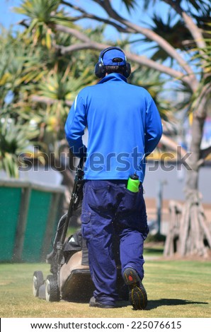 GOLD COAST, AUS - OCT 16 2014:Worker cutting grass during lawn cutting service.85 million households in the US have private lawns