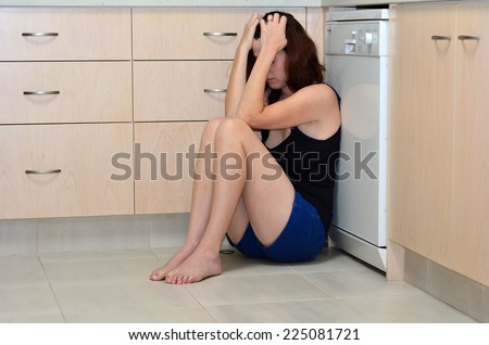 Sad woman sit in her kitchen and covering her face after domestic violence