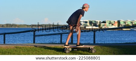 GOLD COAST - OCT 14 2014:Young man rides on motorized skateboard.It\'s a four wheel drive motorised skateboard capable of reaching 50km/h.