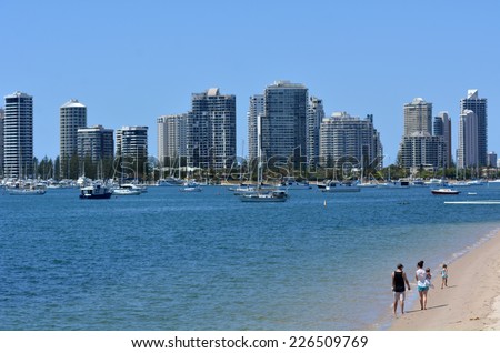 GOLD COAST - OCT 23 2014:Family walks under Surfers Paradise Skyline.It one of Australia\'s iconic coastal tourist destinations, drawing about 10 million tourists every year from all over the world.