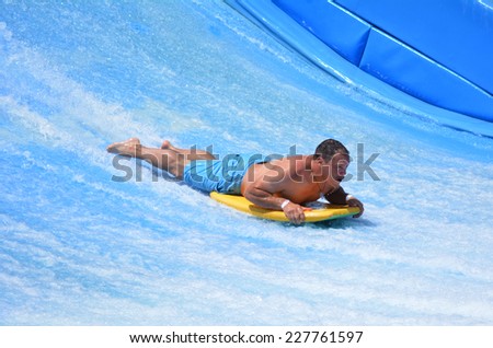 GOLD COAST OCT 29 2014: Man ride a surfing board on FlowRider. It is a water park attraction that simulate the riding of waves in the ocean