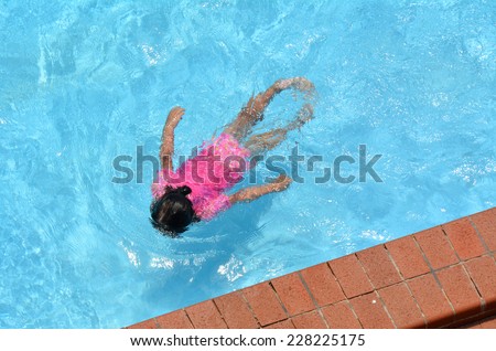 Little girl (age 04) swim in a swimming pool. top view