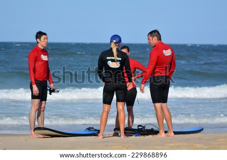 GOLD COAST, AUS - NOV 01 2014:Female wave surfing instructor teaches men and women how to surf in Surfers Paradise, Queensland, Australia.