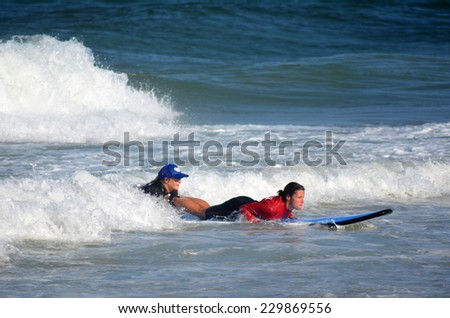 GOLD COAST, AUS - NOV 01 2014:Female wave surfing instructor teaches a woman how to surf in Surfers Paradise, Queensland, Australia.
