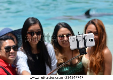 GOLD COAST, AUS - NOV 11 2014:Firends take selfie photo with Dolphin in Sea World Gold coast.Over 1M selfies are taken each day. Instagram has over 53 million photos tagged with the hash tag #selfie.