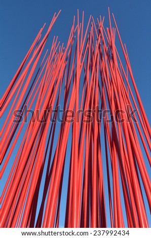 Red metal poles against blue sky. Abstract texture background. vertical