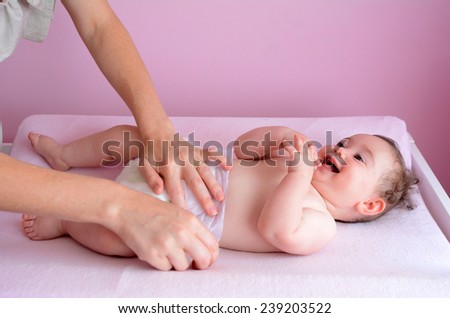 Young mother changes her baby (girl age 06 months) nappy. Concept photo parenthood and motherhood.