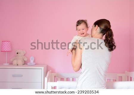 Young mother puts her baby (girl age 06 months) to sleep while she cries. Concept photo parenthood and motherhood.