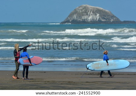 MURIWAI, NZL -  JAN 01 2015:People learn to surf in Muriwai beach.It\'s a very popular beach in New Zealand known for it beauty and for its outdoor activities such as  surfing, swimming and fishing.