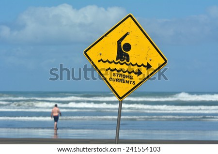 Man walks into the sea where strong currents sign posted. copy space concept conceptual.