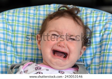 Little baby (girl age 6 months) scream and cry on a baby chair.