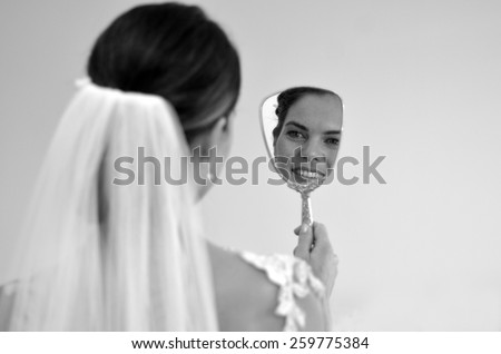 Young bride looks at herself in the mirror on her Wedding Day. Woman,self esteem, self image, wedding and marriage concept. copy space