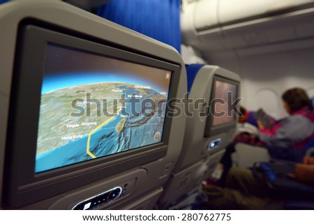 SHANGHAI, CN - MAR 15 2015: Interior of airplane with a route on a screen map and a passengers on seats in the background.The annual risk of being killed in a plane crash  is 1 in 11 million.