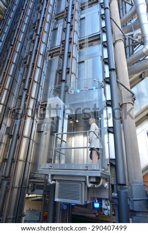 LONDON - MAY 13 2015:Businesswoman in a lift of Lloyds Building.It\'s Lloyds insurance headquarter also knowen as the inside-out building as it\'s lifts, stairs and most of the piping exposed outside.