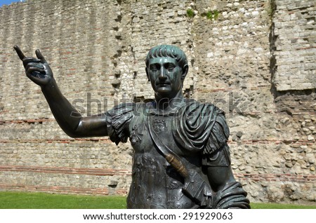 Bronz Statue of Trajan in front of a section of the Roman wall, Tower Hill London, UK.He was Roman emperor (98 -117 AD) presided over the greatest military expansion in Roman history.