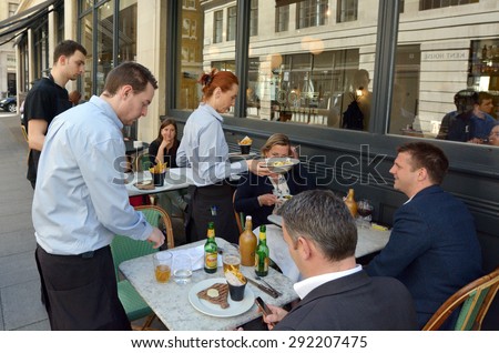 LONDON - MAY 14 2015:Waiters serving food and drinks to people dining in a restaurant in London England UK.The average UK household spends Ã?Â£15.20 a week on restaurants and cafes.