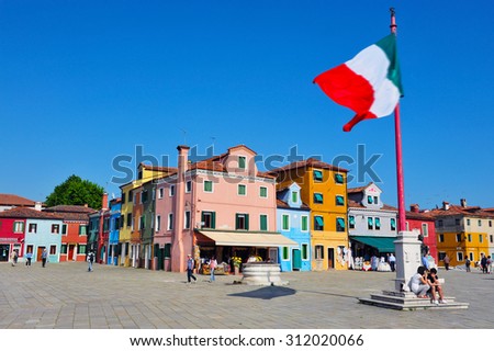 BURANO ISLAND, ITALY - MAY 01 2011:the national flag of Italy fly above Burano island main piazza square. Burano Island is known for its small, colorful brightly painted houses, popular with artists.