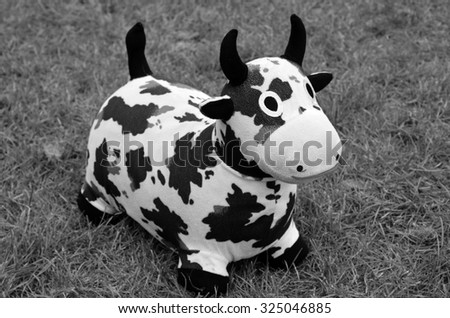 Toy dairy cow on grass background. (BW)