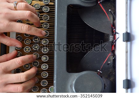 Hand of a young woman writer writing on antique typewriter. Above view - Type Writing Concept