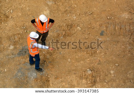 Aerial view of two unrecognised civil engineers inspecting construction site. Building development concept with copy space