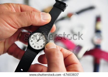 Man hands adjusting the time on a watch. Concept photo of Daylight saving, time alarm travel and changing time zone.