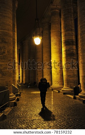 Man walking alone, backpacking across Europe passing through St. Peter\'s Square colossal Tuscan colonnades in the Vatican city state in Rome, Italy