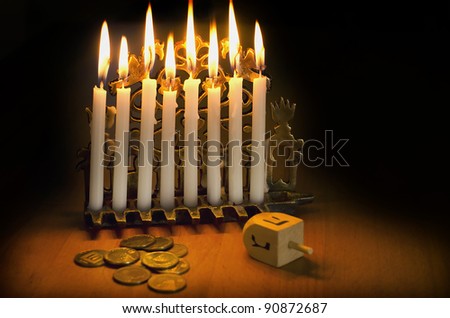 Photo of a dreidel (spinning top), gelts (candy coins) and an ancient brass menorah for the Jewish holiday of Hanukkah.