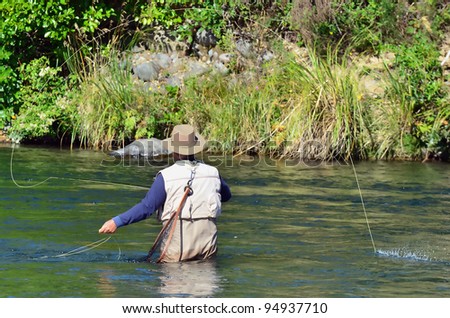 A fisherman fly fishes for Trout fish in Tongariro river near Taupo lake, New Zealand.