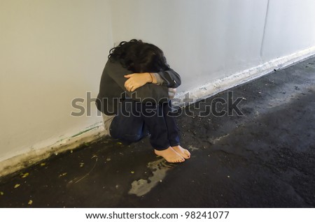 stock photo : Crime scene concept photo of rape victim. A sad woman sits on the floor of a dark tunnel.