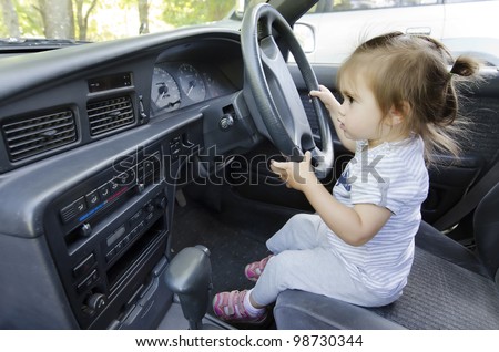 A little girl pretends to drive a car. Concept photo of children education, learning , drive a car,funny, happy, play, happiness, car insurance
