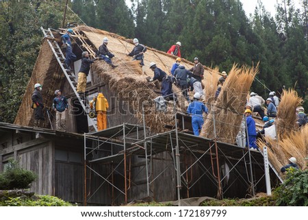 Shirakawa go, Japan - 27 October 2013. A group of workers repairing  Gassho-zukuri  a wooden house with roof made of straw, in the world heritage village in Gifu Takayama Japan