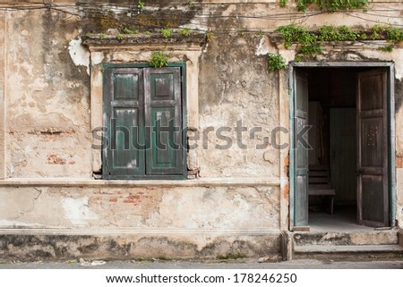 Old green window and open door on old bricks and cement wall