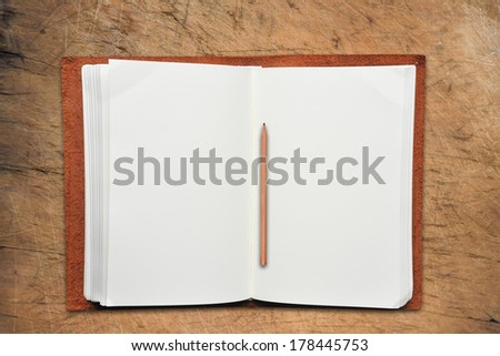 Open Leather Book with Vintage Pencil on Old Wooden Table.