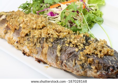 Fried fish topped with garlic served on white dish