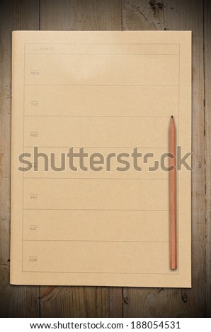 A closed vintage calendar book or notebook with pencil on old wooden table.