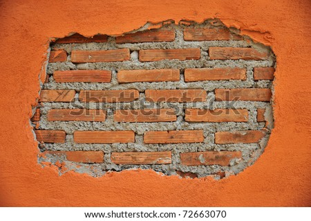 A  cracked wall reveal a brick wall inside