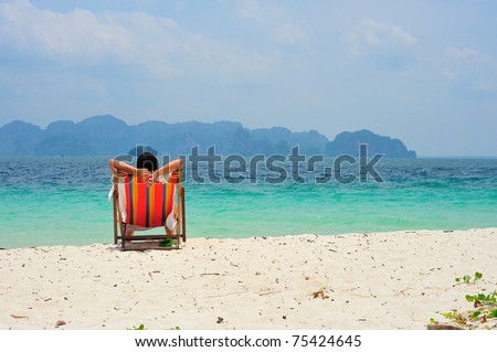 A man sitting on beach chair looking into sea