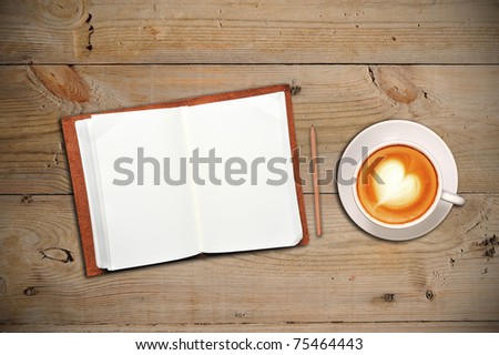Open notebook with cup of coffee on a wooden floor