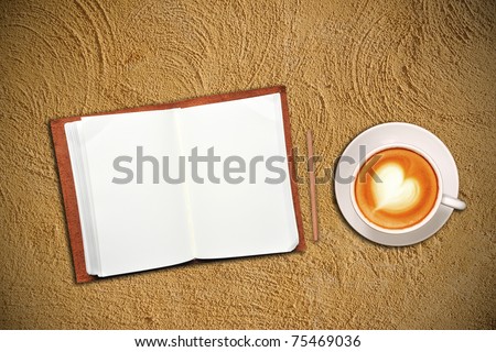 Open notebook with cup of coffee on sand
