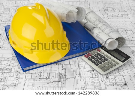 Yellow helmet, calculator, blue folder document and project drawings